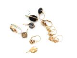 several pairs of earrings with black stones on them on a white surface