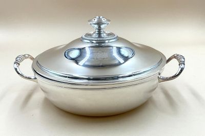 a silver casserole with a lid on a white table