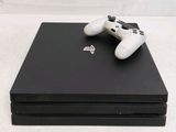 two white controllers on top of a black video game console