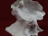 a white ceramic sculpture of a bird on a tree stump