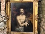 tableau représentant Jésus, dans un cadre doré, accroché à un mur de pierre