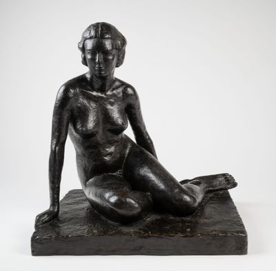 une sculpture noire représentant une femme assise sur un rocher