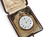 une boîte contenant une horloge, posée sur une surface blanche