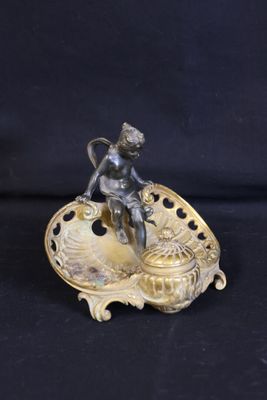 an antique bronze figurine of a boy on a shell