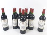 six bottles of wine are lined up in a row on a white surface