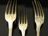 three forks are sitting next to each other on a black surface