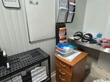 an image of a room with a refrigerator, desk, and other items