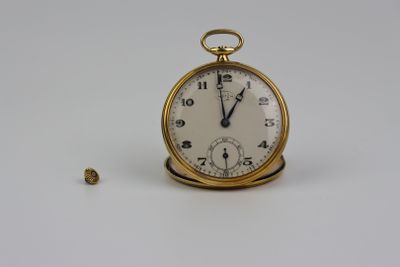 une montre de poche en or posée sur une surface blanche