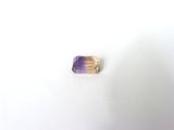 un gros plan d'une bague violette et dorée posée sur une surface blanche