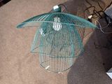 un oiseau dans une cage posée par terre à côté d'un ordinateur portable