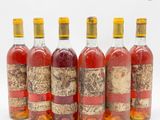 six bouteilles de vin sont alignées sur une surface blanche