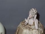 a figurine of a woman sitting on a table next to a vase