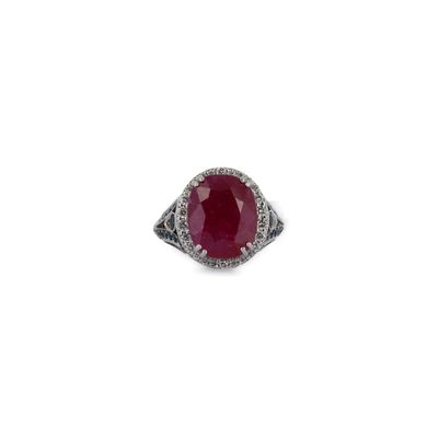 gros plan d'une bague avec une pierre rouge entourée de diamants