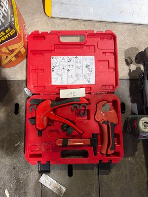 une boîte à outils rouge contenant des outils, posée par terre