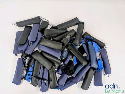 une pile de combinaisons de plongée bleues et noires posées sur une surface blanche