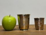 three cups and an apple sitting on a table