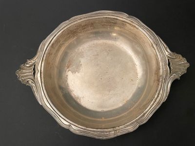 un plat en argent ancien posé sur une table noire, sur fond noir
