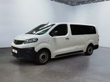La camionnette blanche est garée dans une grande pièce aux murs blancs.