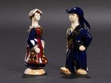 two figurines of a man and a woman standing next to each other