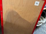a red refrigerator sitting on the floor next to a red truck