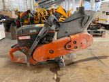 an orange and black chainsaw sitting on top of a floor in a warehouse