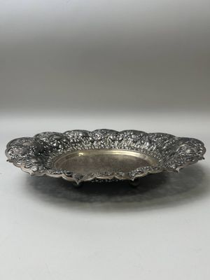 une assiette en argent posée sur une table, sur fond blanc