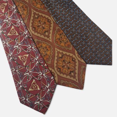 three different colored ties with designs on them on a white background