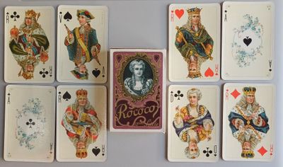 des cartes à jouer sont disposées sur une table où figure une image de la dame de pique