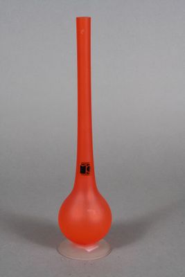 an orange glass vase with a black top on a white surface
