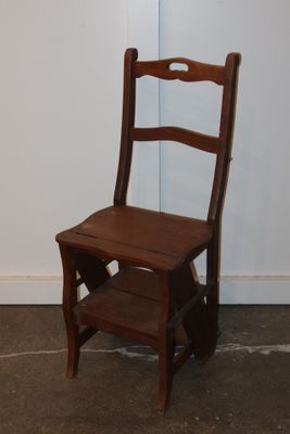 a small wooden chair sitting in front of a white wall