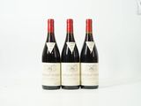 trois bouteilles de vin rouge posées sur une table blanche