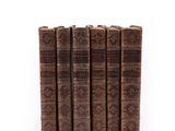 six old books stacked on top of each other on a white surface