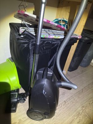 a green vacuum and a black bag on the floor