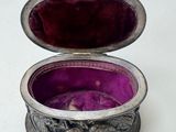 a small silver box with a purple velvet inside