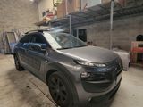 La voiture grise est garée dans le garage, devant des cartons.