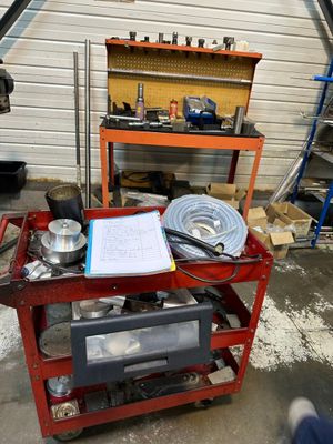 un chariot de chantier rouge chargé d'outils, dans un garage
