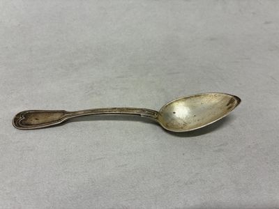 une vieille cuillère en argent avec un manche, posée sur une table