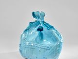 un sac bleu rempli de nourriture posé sur une surface blanche