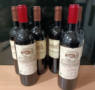 Quatre bouteilles de vin rouge sont alignées sur une table en bois