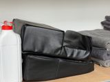 a black leather chair with a bottle of cleaner next to a stack of towels