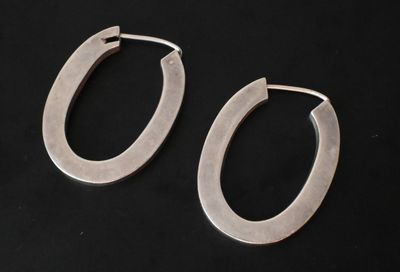 une paire de boucles d'oreilles créoles en argent sur fond noir