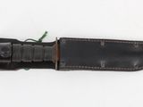 an old knife with a leather sheath on a white surface