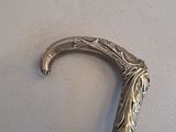 a silver and black walking stick on a white surface
