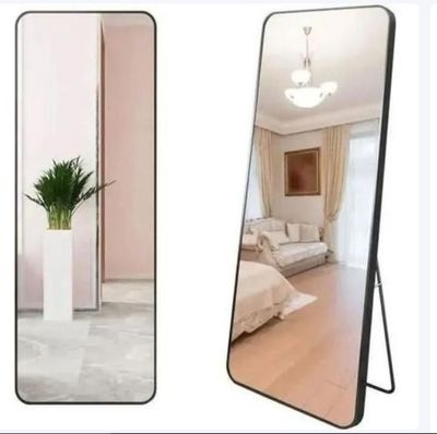 un miroir posé au sol à côté d'une plante