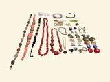 many different necklaces and bracelets laid out on a table