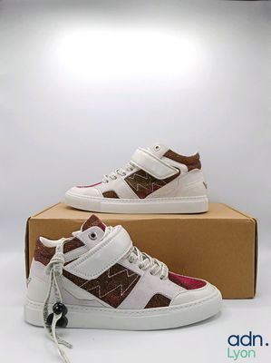 une paire de baskets pour enfants, blanches et marron, dans une boîte