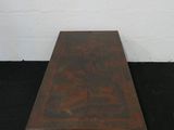 une table basse ancienne en bois à deux pieds, posée sur un tapis noir
