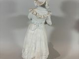 a white statue of a woman with a hat and dress