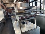 une cuisine professionnelle équipée de plans de travail en inox et d'un grand grill