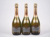 trois bouteilles de champagne posées les unes à côté des autres sur une surface blanche